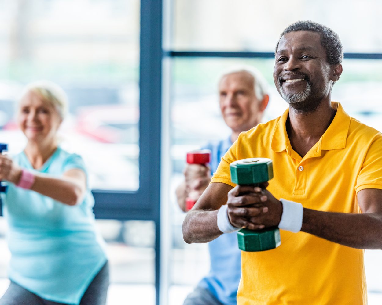 african american sportsman and his friends exercising with dumbbells at gym