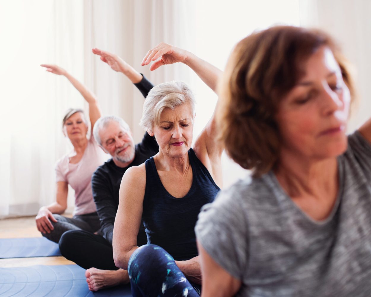 Four older people taking part in a yoga class