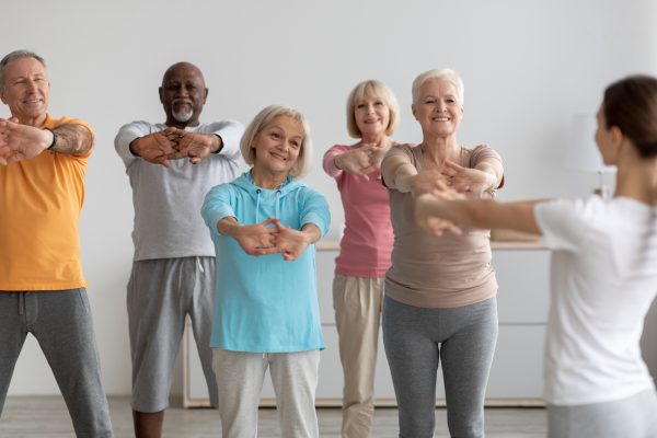 Sporty elderly people having fitness class, training with instructor