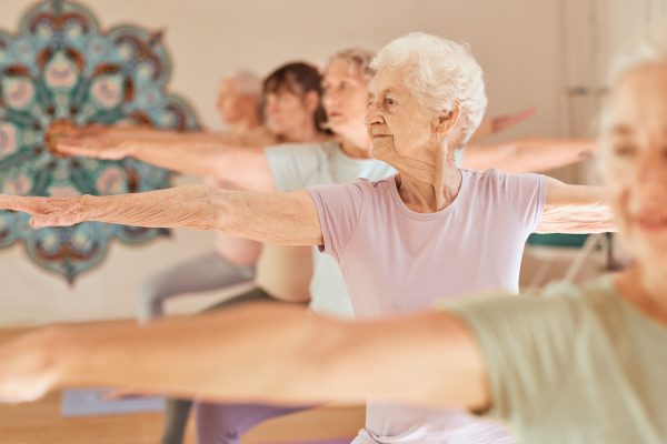 An older woman joins friends in a group exercise class.