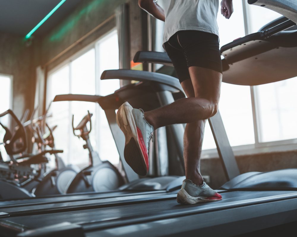 Close up of feet, sportman runner running on treadmill in fitness club. Cardio workout. Healthy lifestyle, guy training in gym. Sport running concept