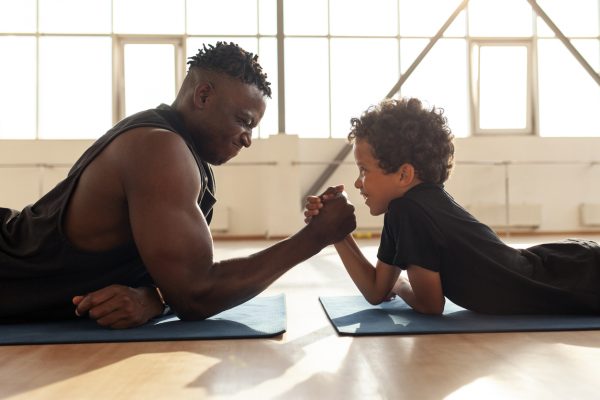 african american boy 9 years old competes with dad in arm wrestling, father trains his son and tests his strength