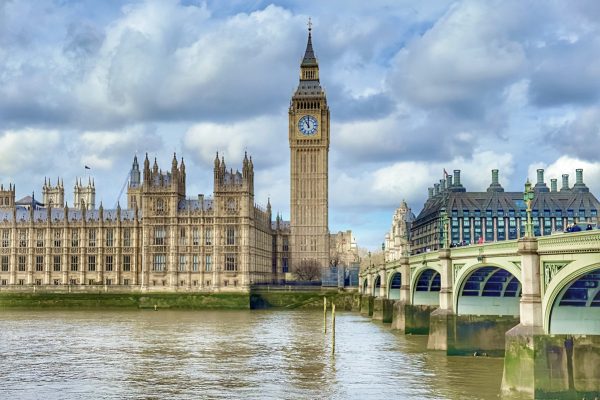 A view of Big Ben between the Houses of Parliament and Westminster Bridge across the River Thames in Westminster, London, UK.