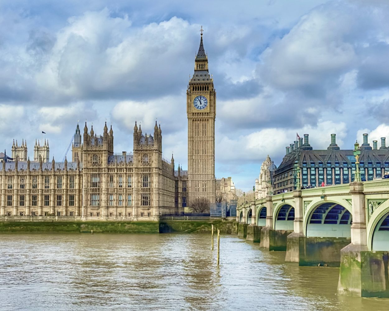 A view of Big Ben between the Houses of Parliament and Westminster Bridge across the River Thames in Westminster, London, UK.
