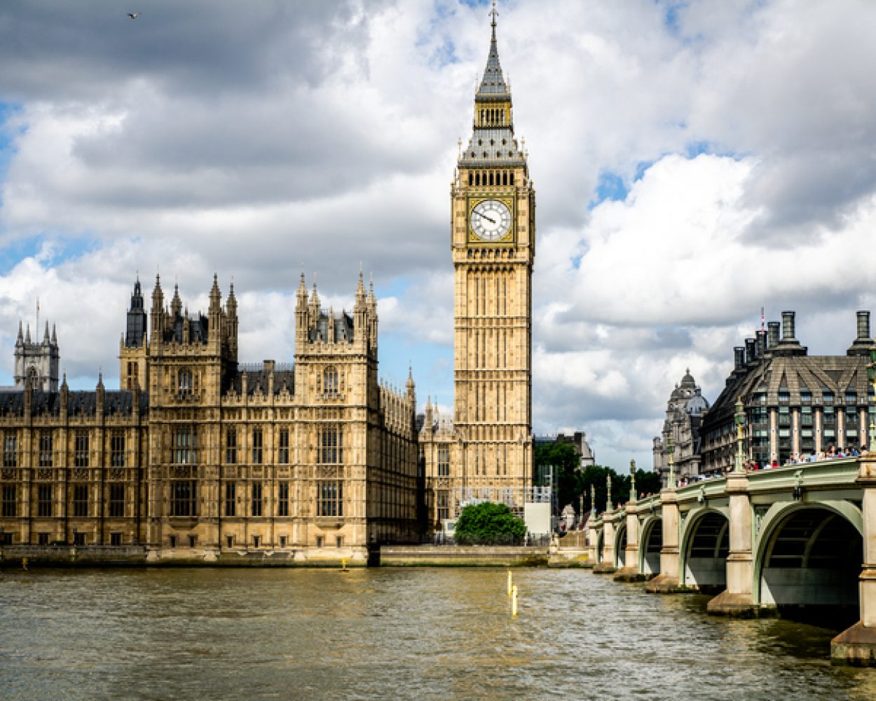 Bridge Over River In City Against Cloudy Sky