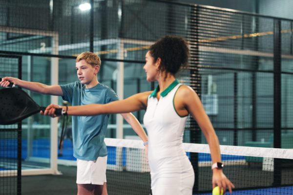 Coach, child and woman with padel racket on court for learning sports, training and exercise. Personal trainer, fitness and person with children at practice for playing game, tournament and match