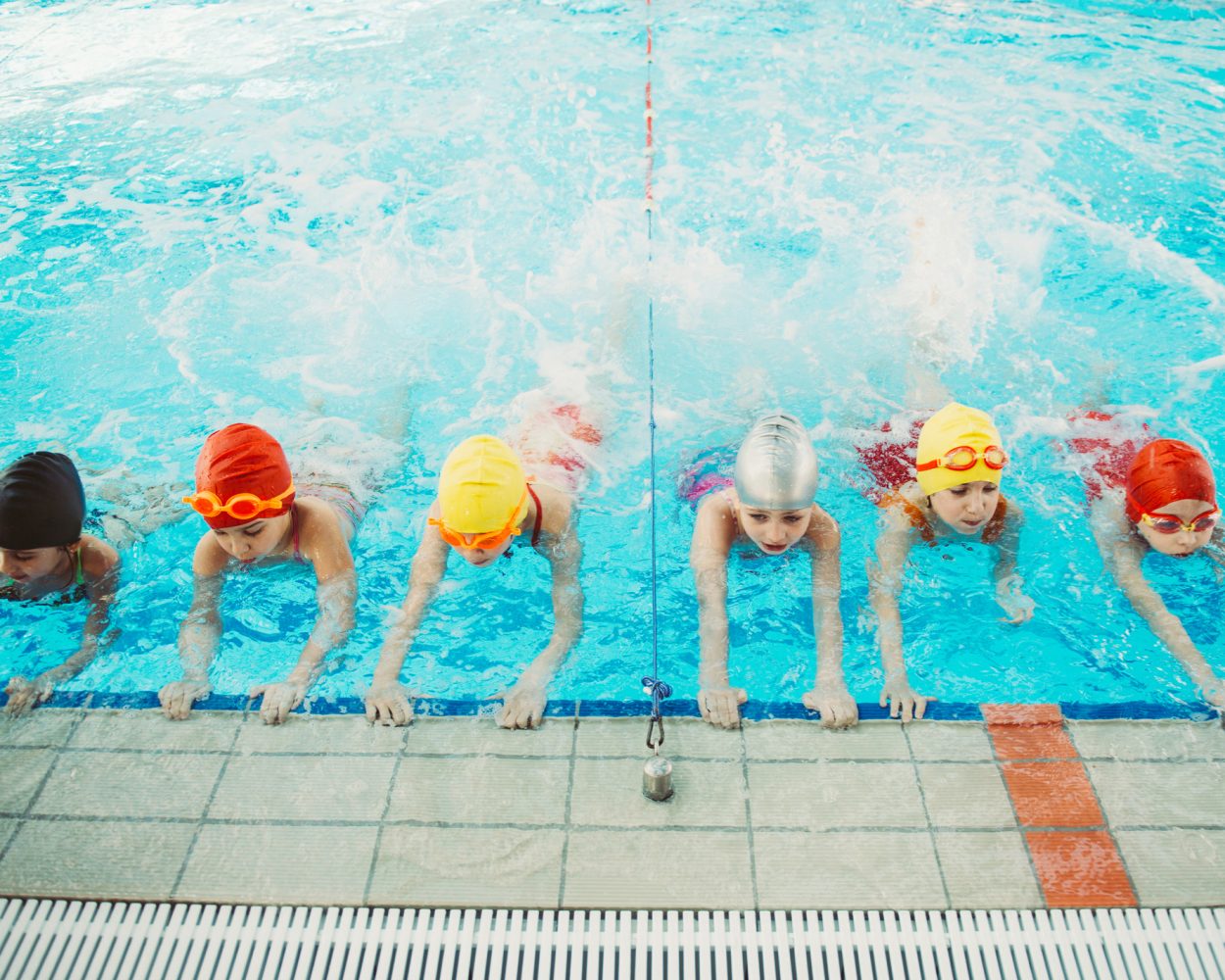 happy children kids group at swimming pool class learning to swim