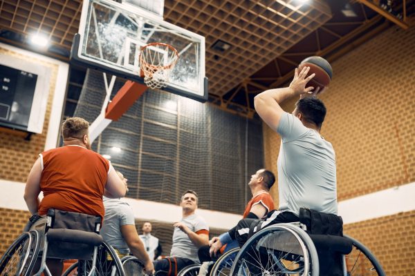 Below view of disabled men playing wheelchair basketball match on the court.